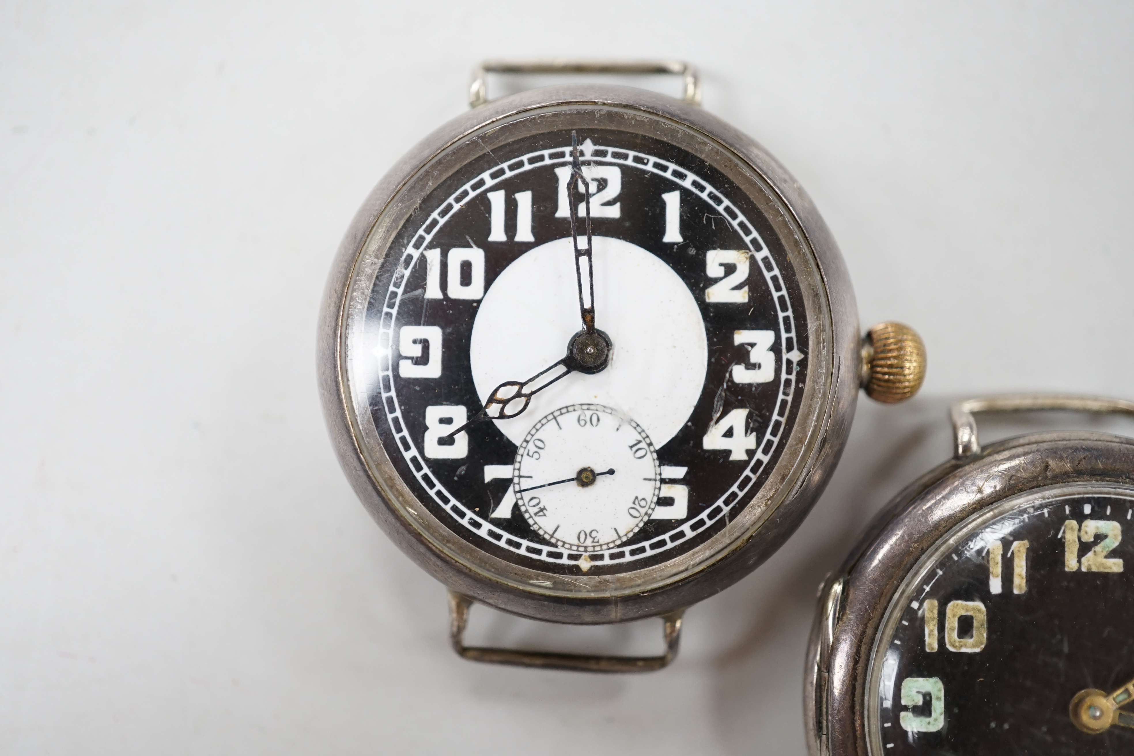 Two early 20th century silver manual wind wrist watches including black dial, both with subsidiary seconds, no straps.